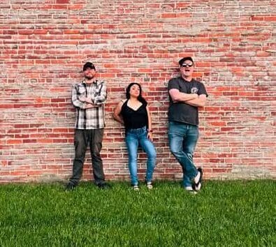 picture of band 'New Groove' in front of a brick wall, standing on grass